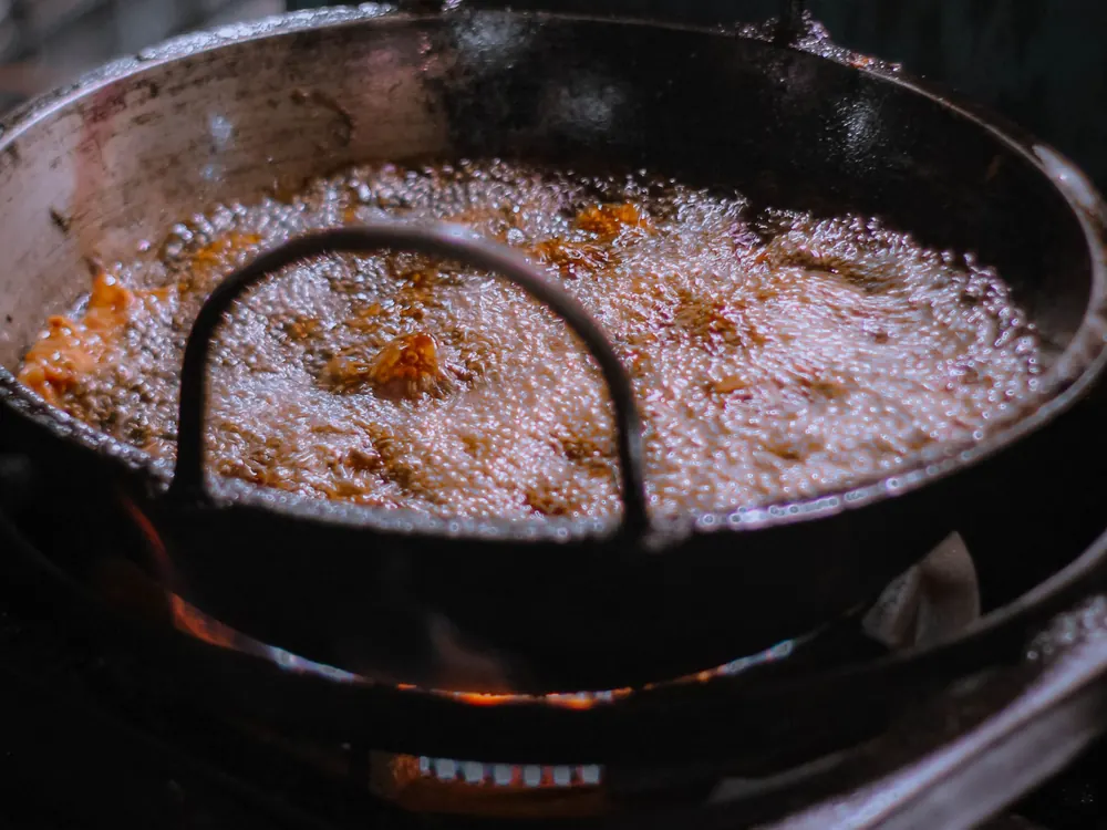 Snacks frying in a traditional kadai over an open flame